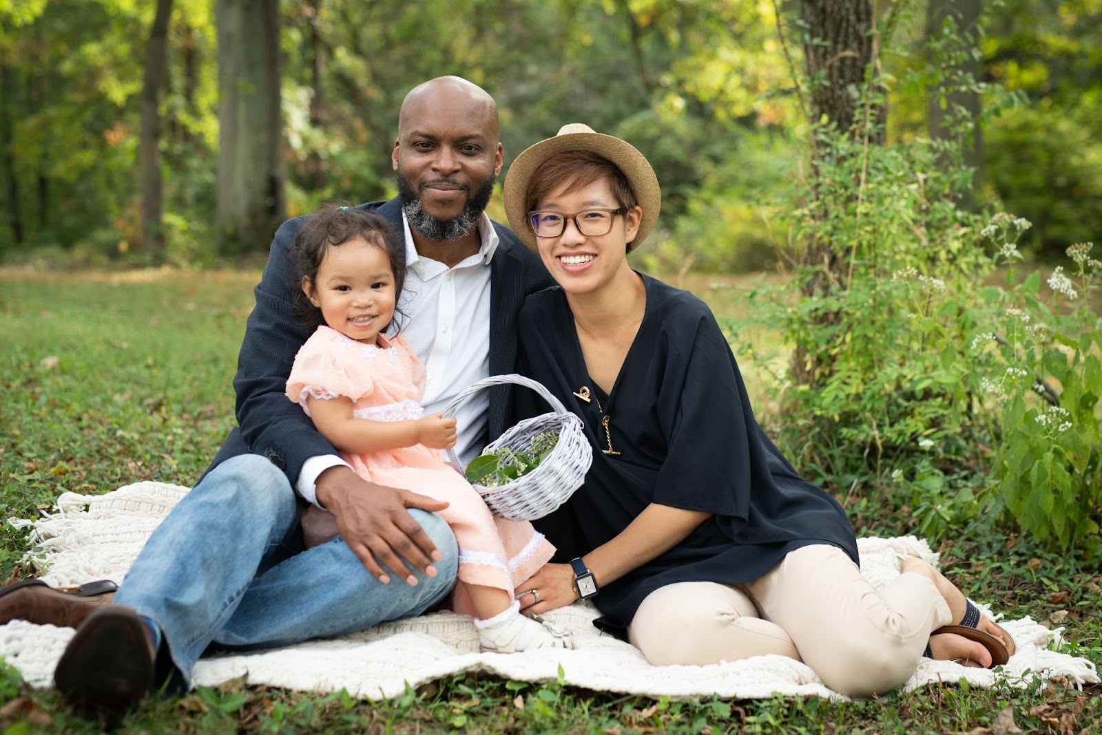 A multicultural family: a Jamaican father, Chinese mother, and the daughter sits on the father’s lap. 