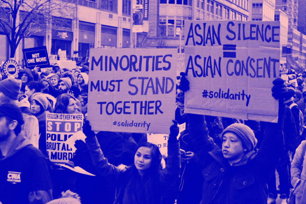 Protestors holding signs saying "Minorities must stand together" and "Asian silence = Asian Consent" in a show of solidarity
