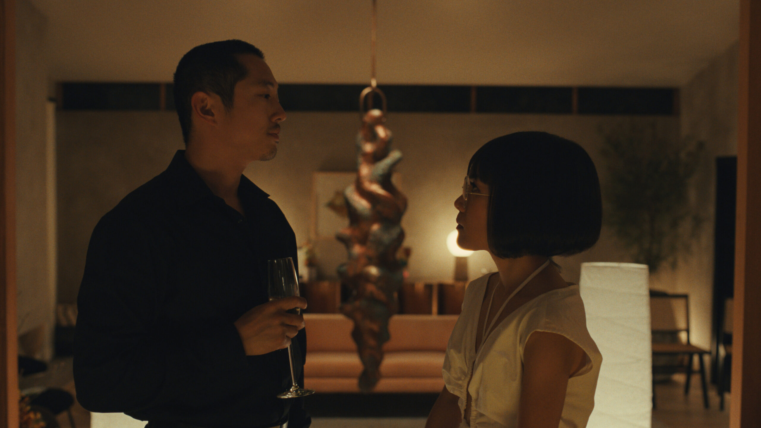 Steven Yeun as Danny and Ali Wong as Amy having a conversation at a dinner party. Beef on Netflix.