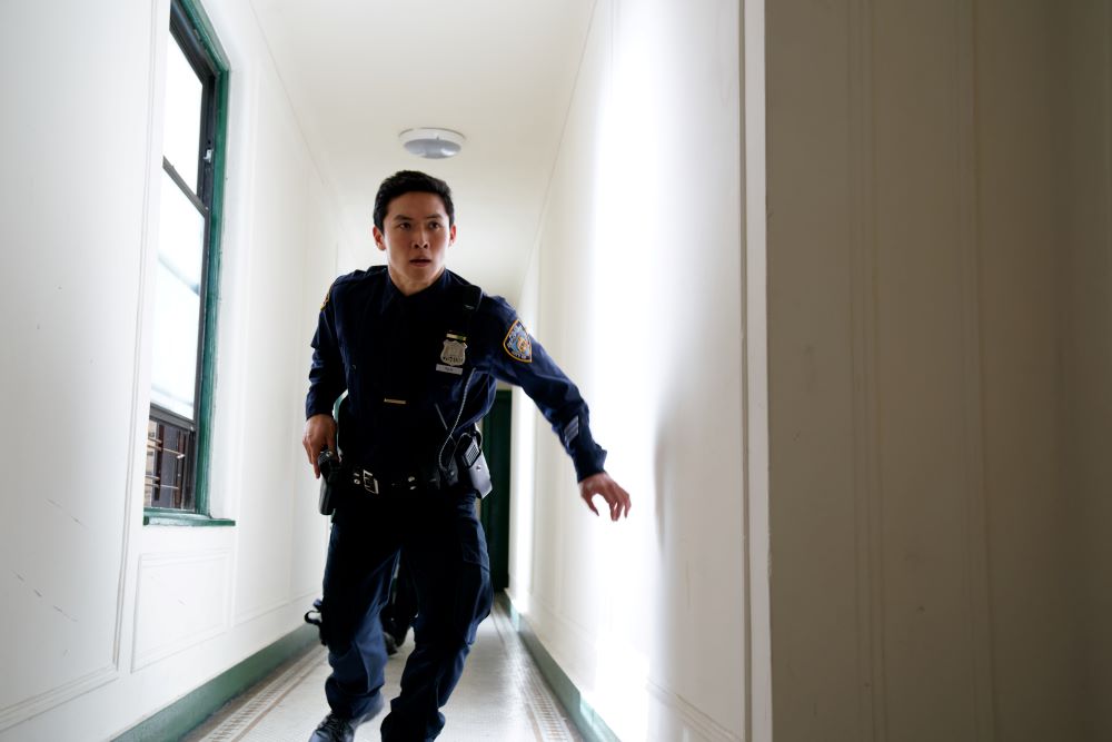 Mike Tan, played by Kenny Leu, runs down a hallway reaching for his gun in the film A Shot Through the Wall.