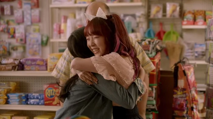 A scene from a TV show Kim's Convenience Store. Janet's cousin from Korea is hugging her in front of Janet's father. 
