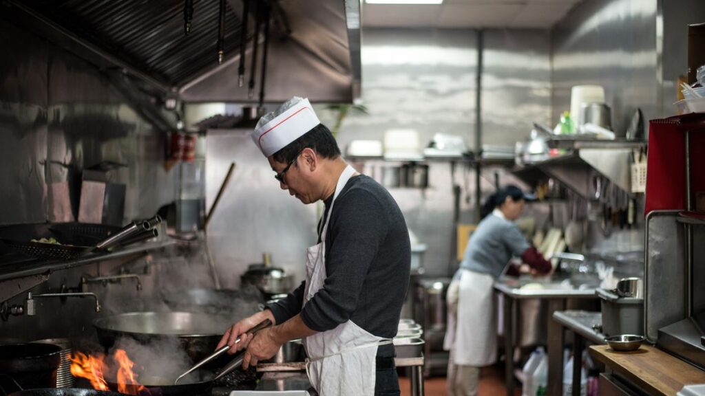 A cook named Mr. Chen mans the wok in the kitchen at Happy Wok in Crown Heights.