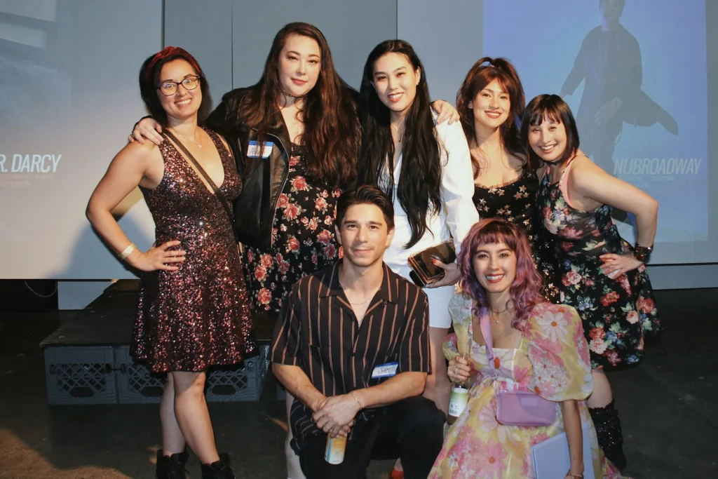 A vibrant, neon-colored event flyer for Mixed Asian Day 2025 with a pink and lime green background. The flyer lists activities happening from 12:00 PM to 6:30 PM, including yoga, author panels, adoptee voices conversations, discussions on family expectations, and a final closing mixer. The graphic uses a funky, colorful font, giving it a playful retro aesthetic. The event highlights identity, community, and creativity within the mixed Asian experience.