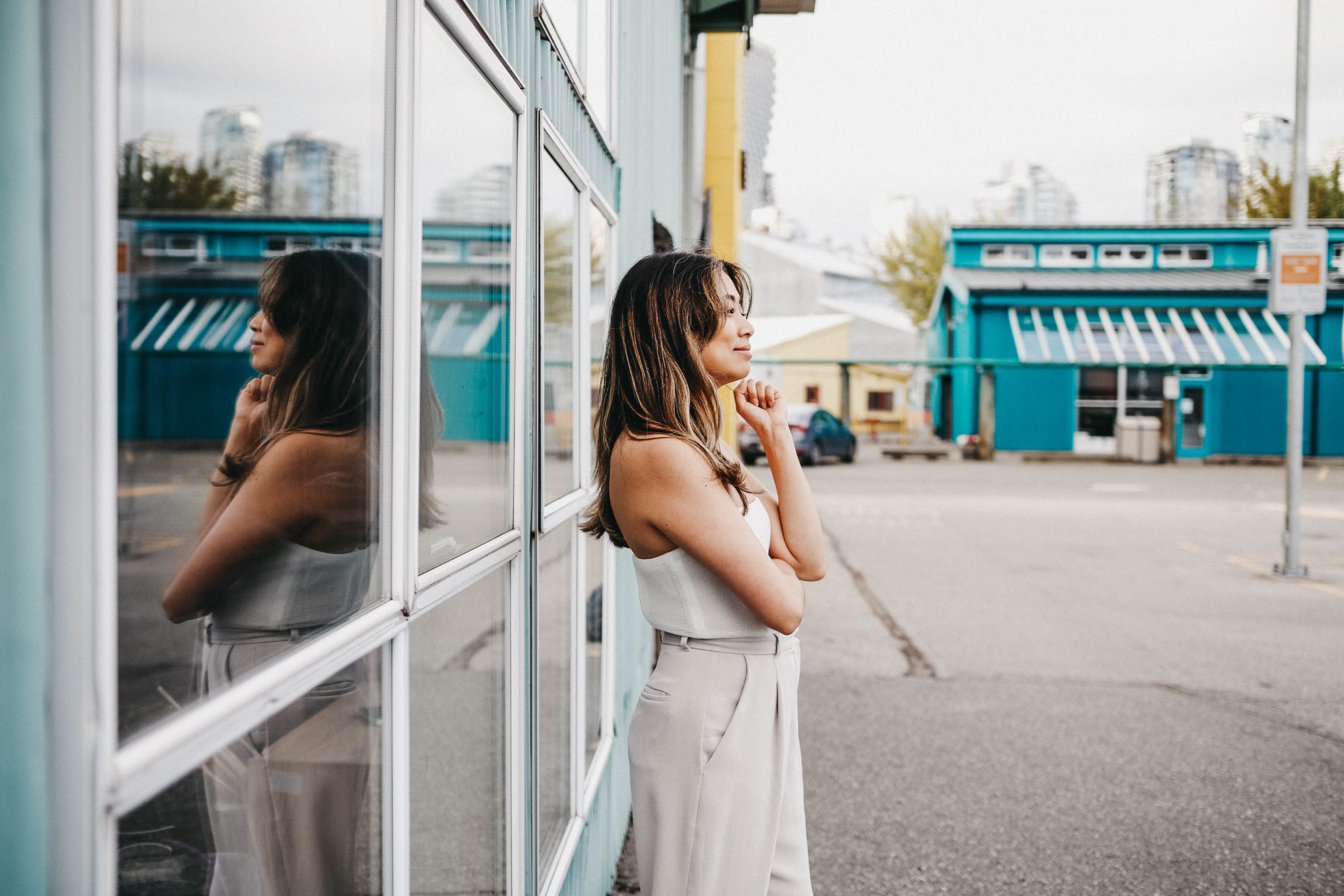 Woman wearing white standing outside a building next to windows