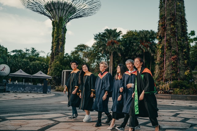 A group of recent university graduates laughing and walking. 