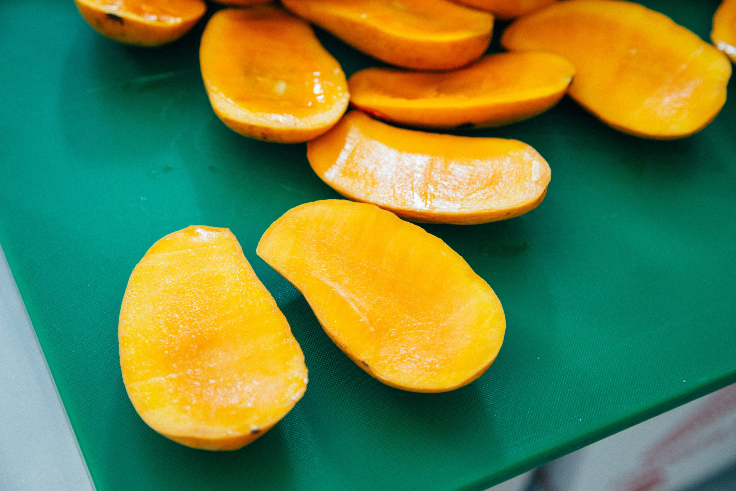 Cut mangoes on a green cutting board