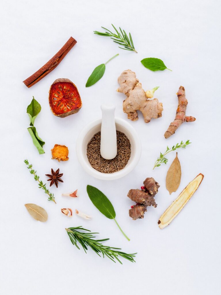 a white mortar and pestle surrounded by various herbs