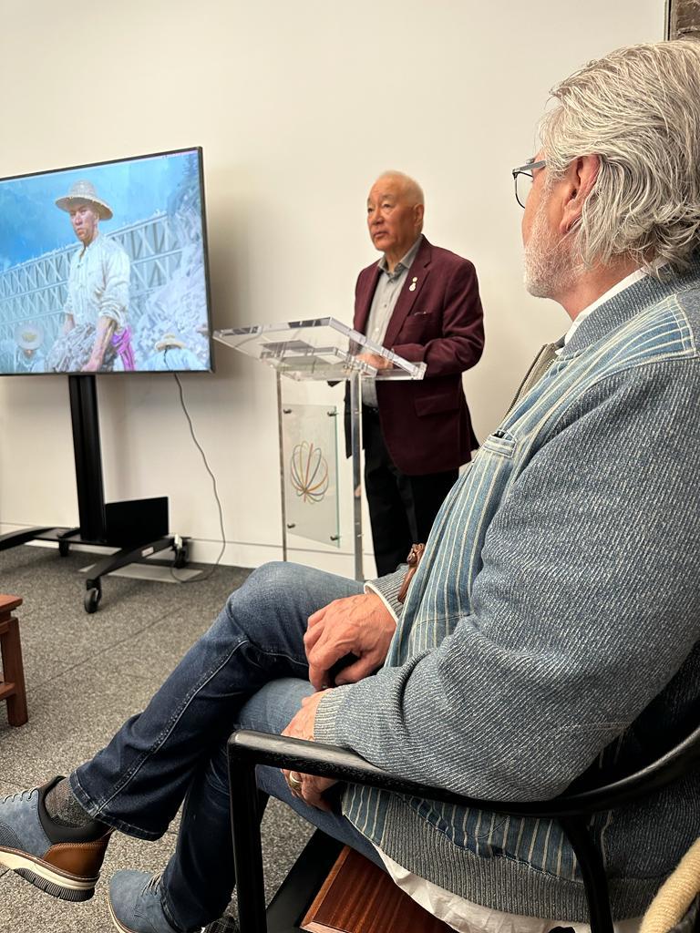 A person sitting in a chair and looking at a television
Description automatically generated