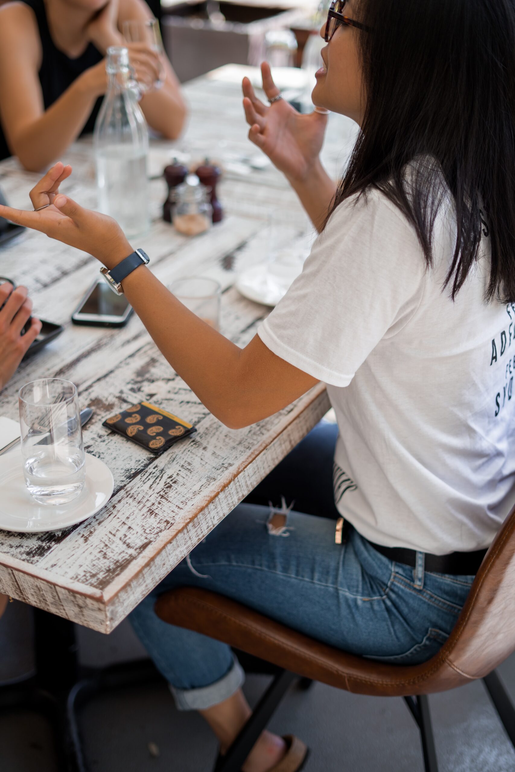 The picture of a woman gesticulating and trying to convey an idea at a table. 