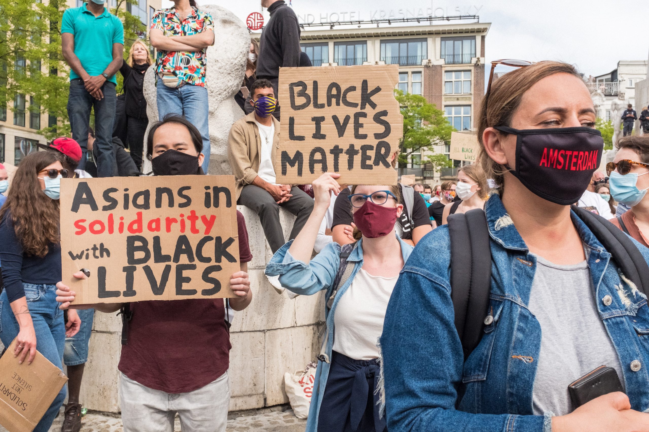 Black Lives Matter protest with a protestor holding a sign saying "Asians in solidarity with black lives"
