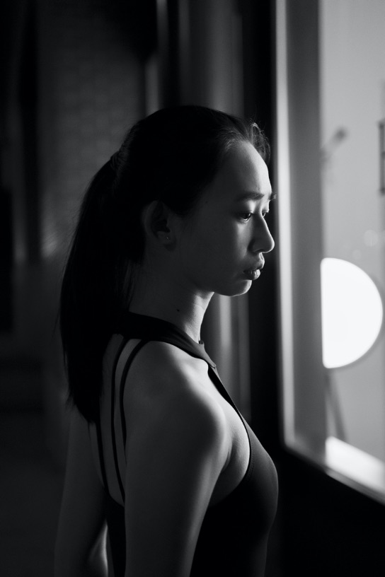 Asian girl looks out a window. Black and white. 