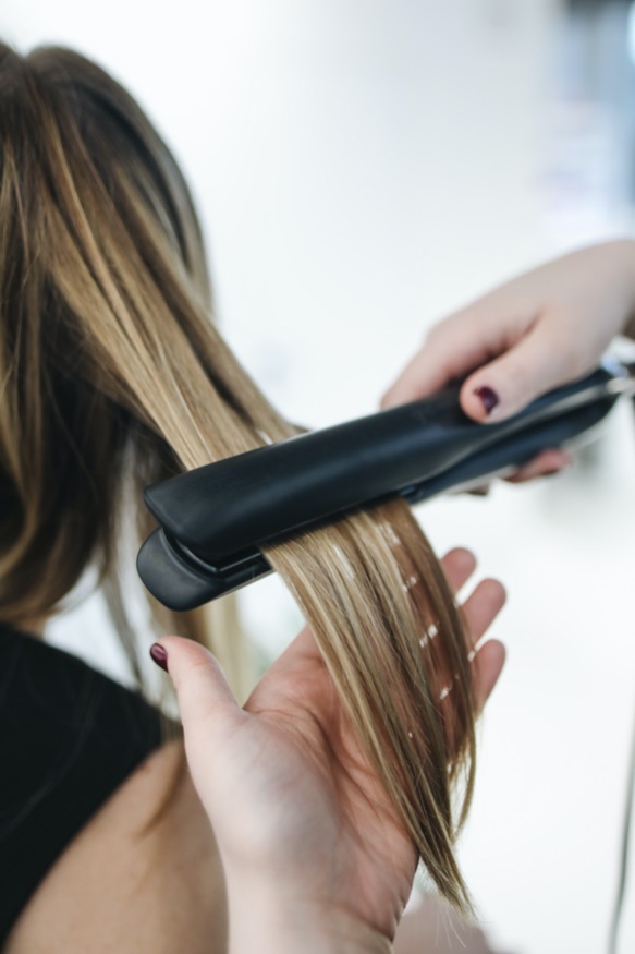 woman straightening her hair with straightening iron