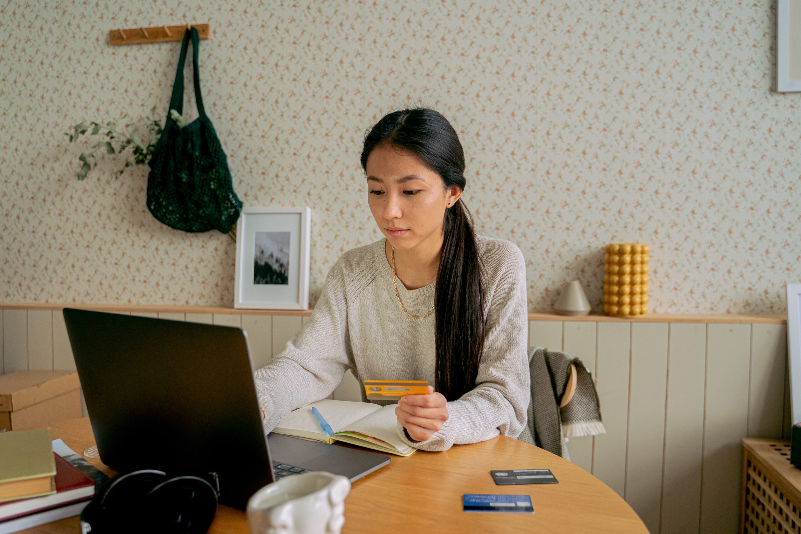 Asian American woman looking at her laptop and paying with credit cards