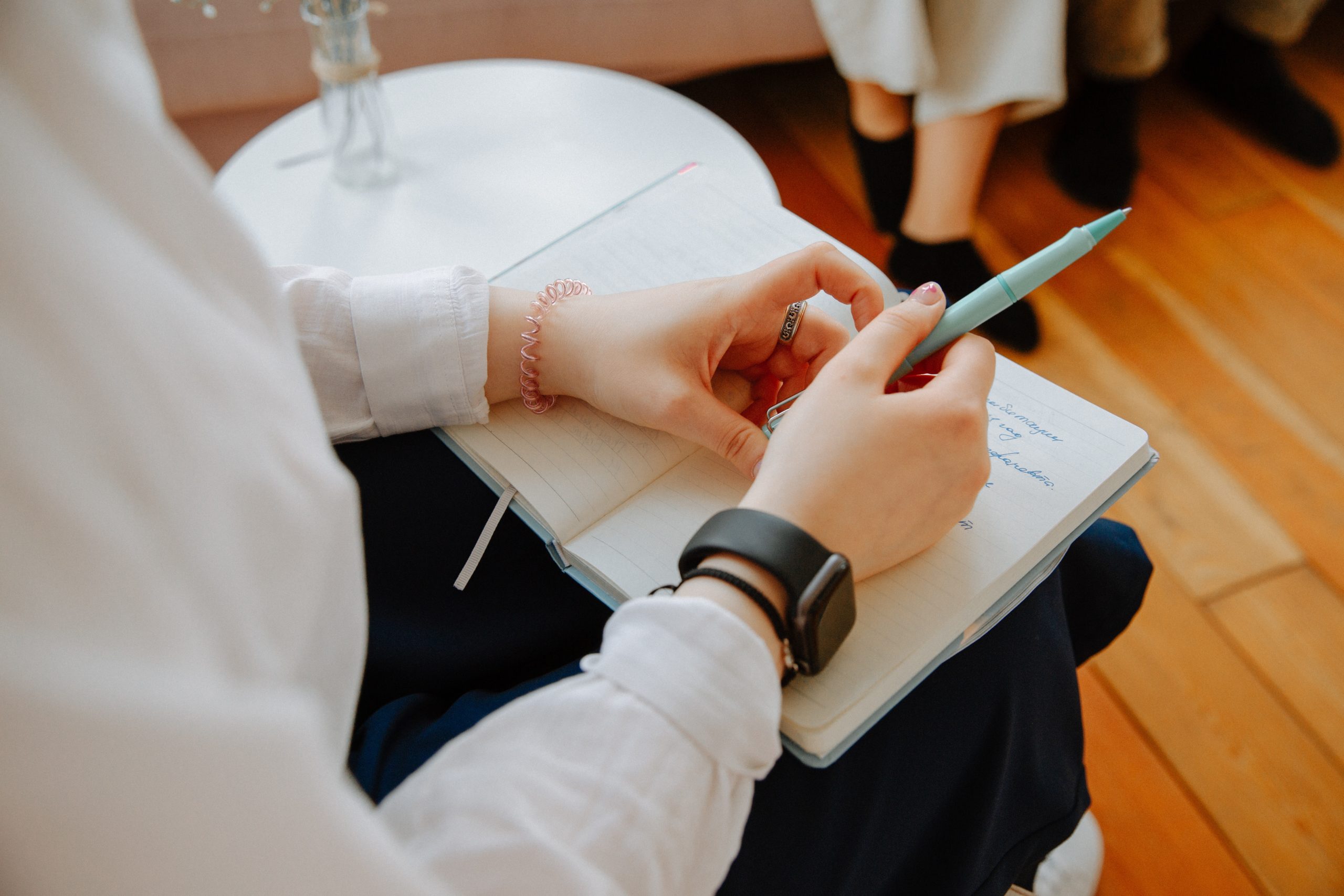 Person holding a journal with pen in an office.