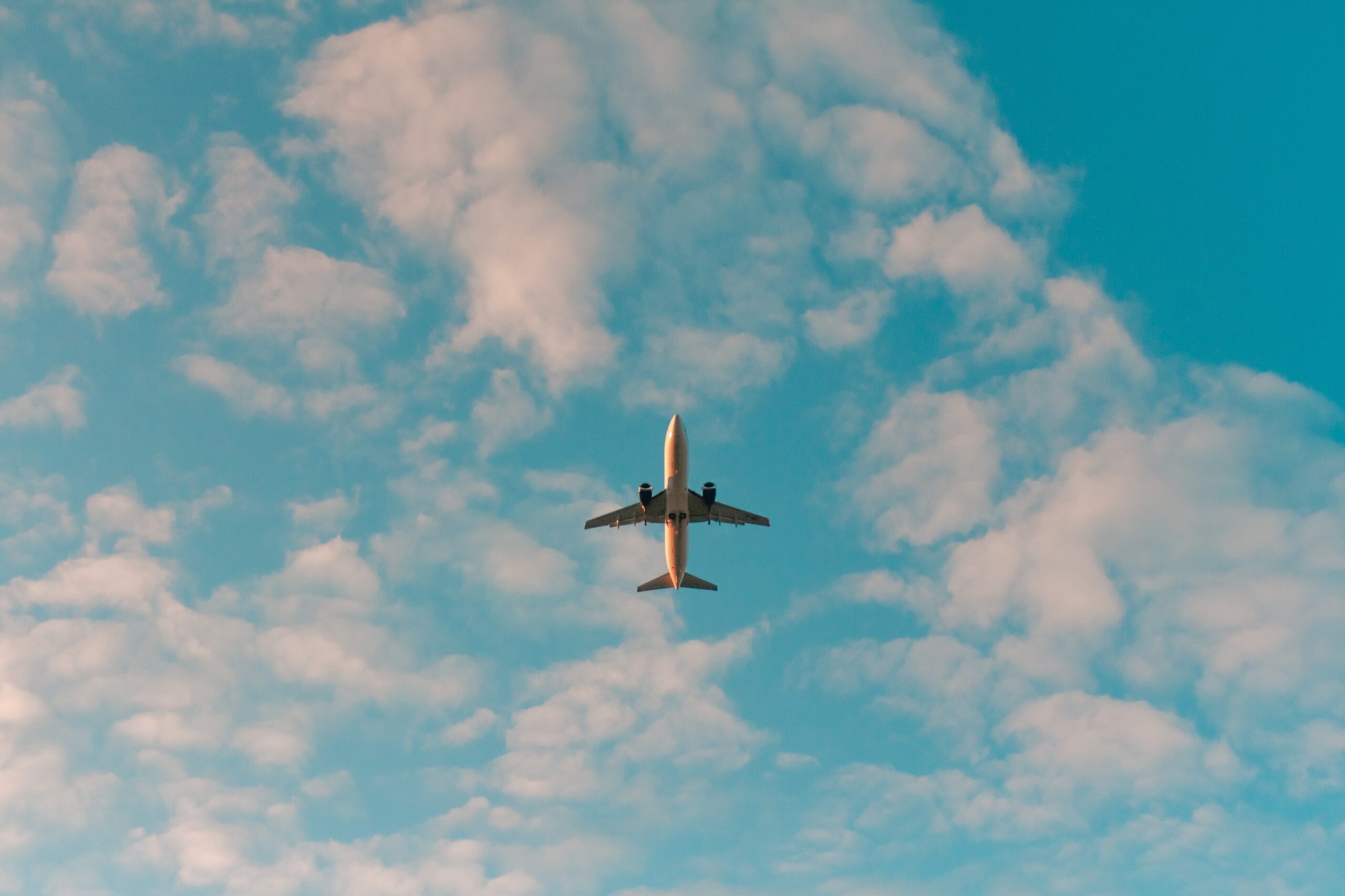 Image of a plane from below. A large blue sky can be seen in the background. 