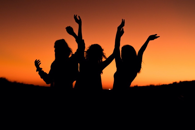 Three girls' silhouettes against a sunset. 