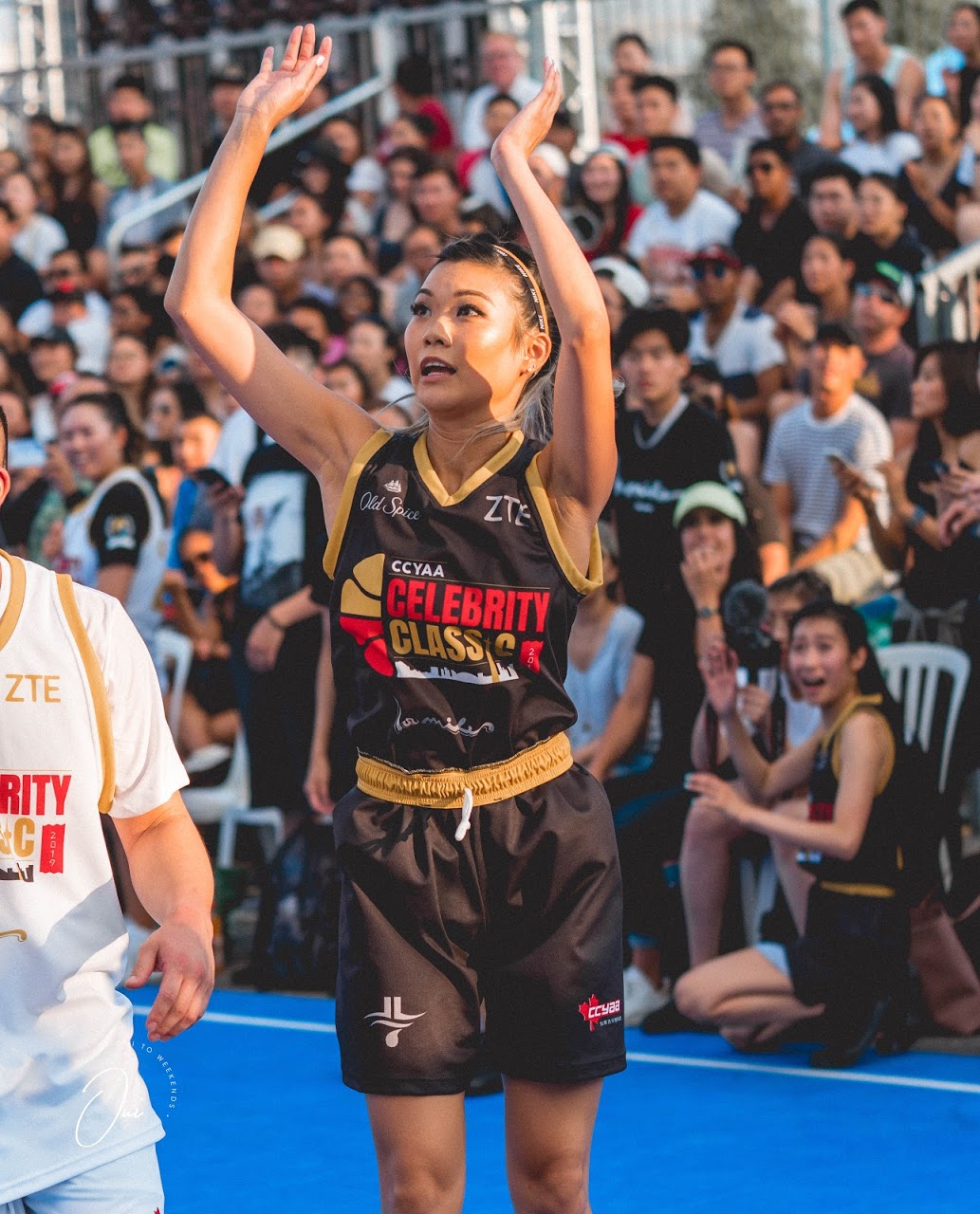 A woman and her young daughter, both in red clothing, sit on a ledge outdoors eating from white bowls at a cultural event. Booths, tents, and people can be seen in the background, with a warm and nostalgic atmosphere. The photo appears to be from the late 1990s.